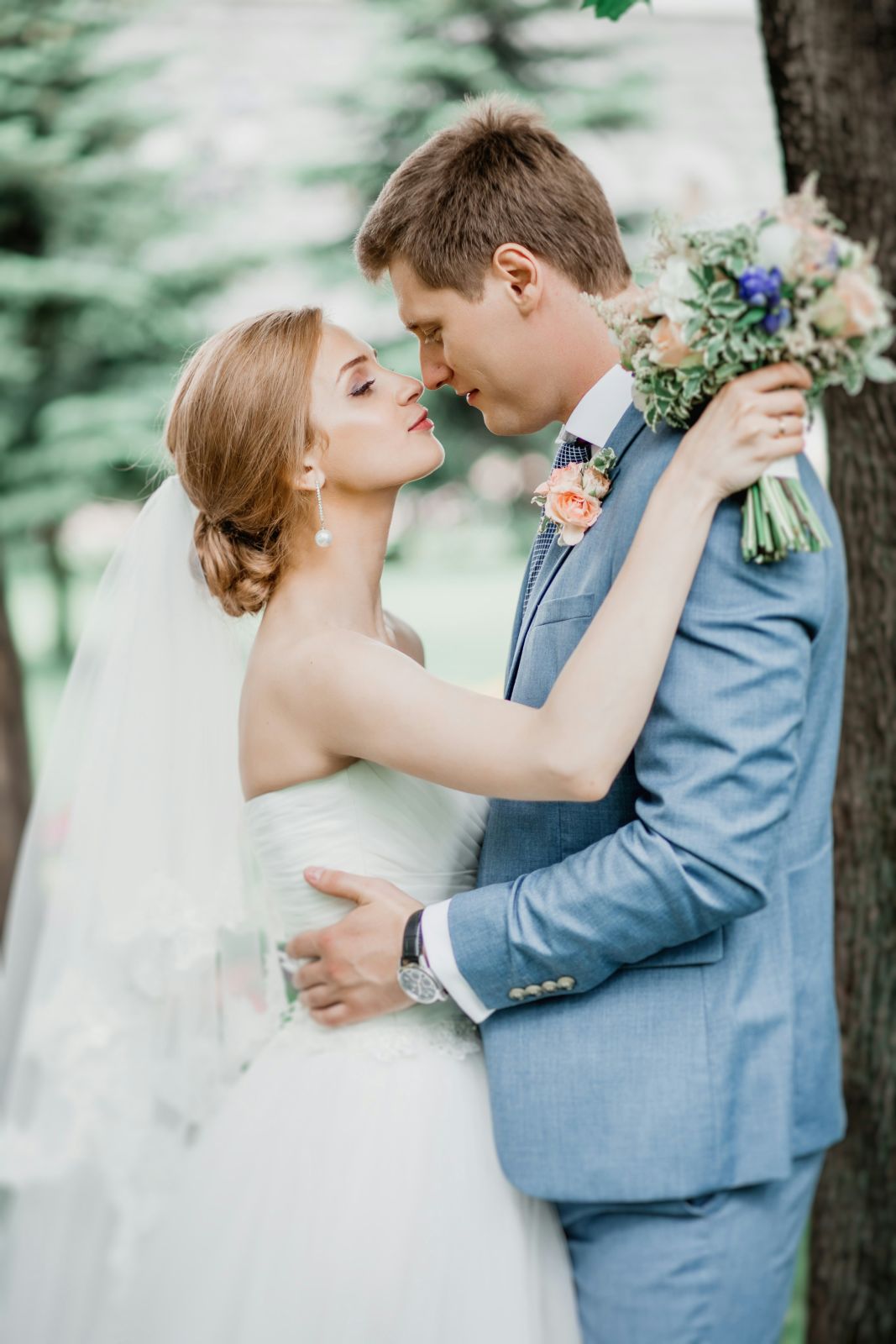 Bride and groom with a bouquet in a green garden