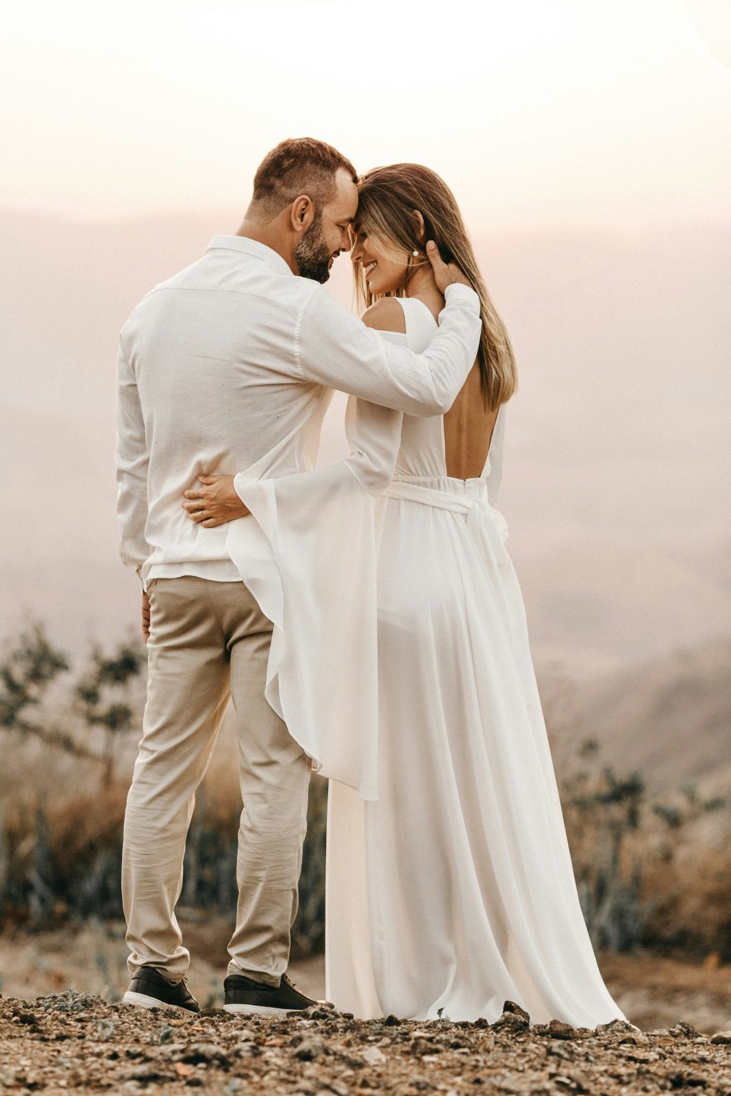 Bride and groom holding each other on a hilltop at dusk